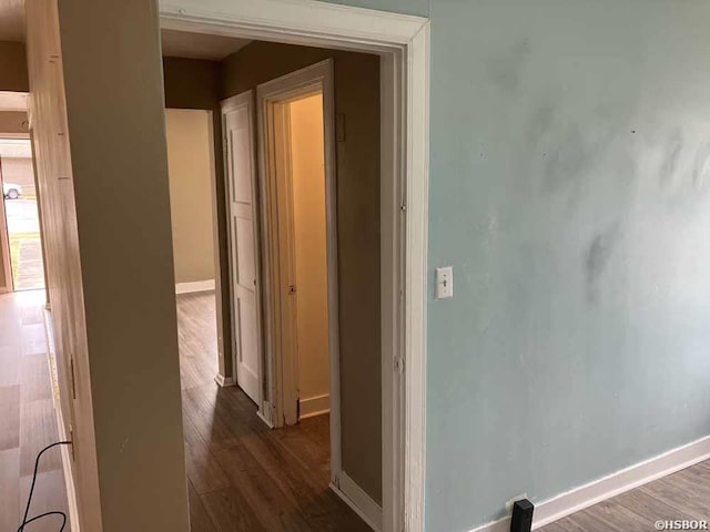 corridor with dark wood-style floors and baseboards