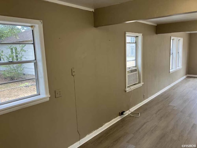 interior space featuring cooling unit, crown molding, baseboards, and wood finished floors