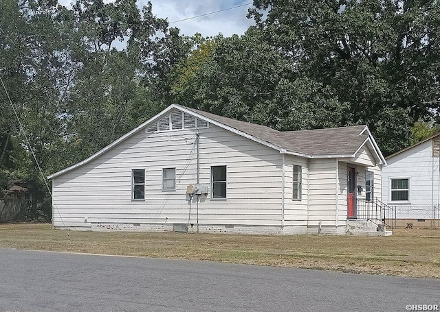 view of side of home with crawl space, roof with shingles, and a yard