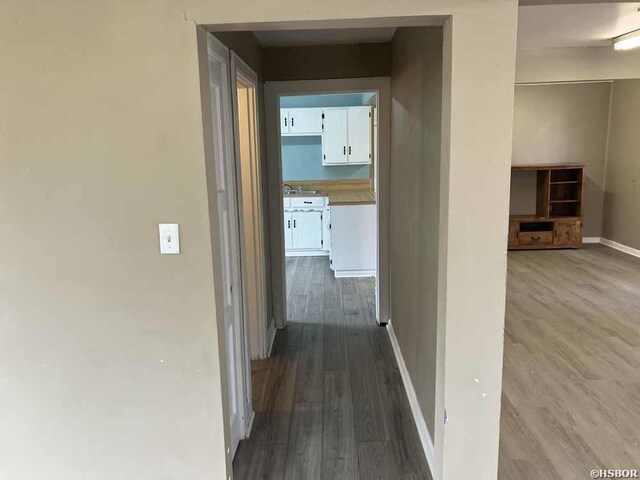 hallway featuring dark wood-style floors and baseboards