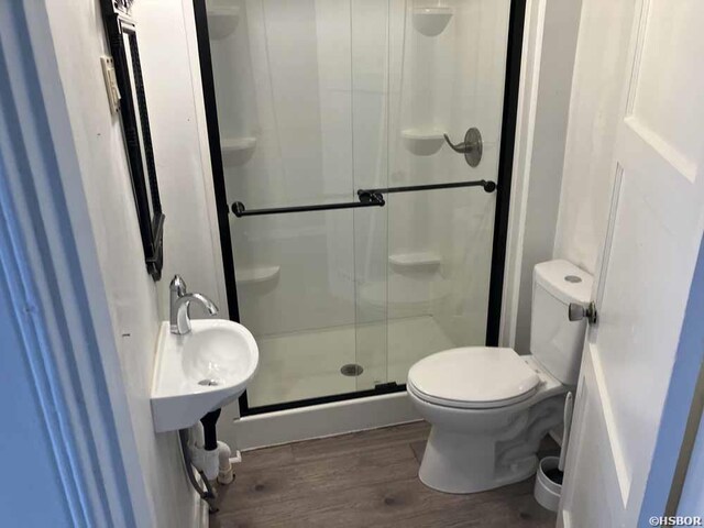 bathroom featuring toilet, a shower stall, and wood finished floors