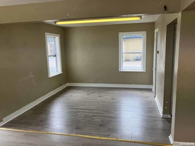 unfurnished room with dark wood-style floors and baseboards