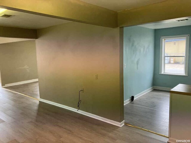 unfurnished room featuring dark wood-type flooring, visible vents, and baseboards