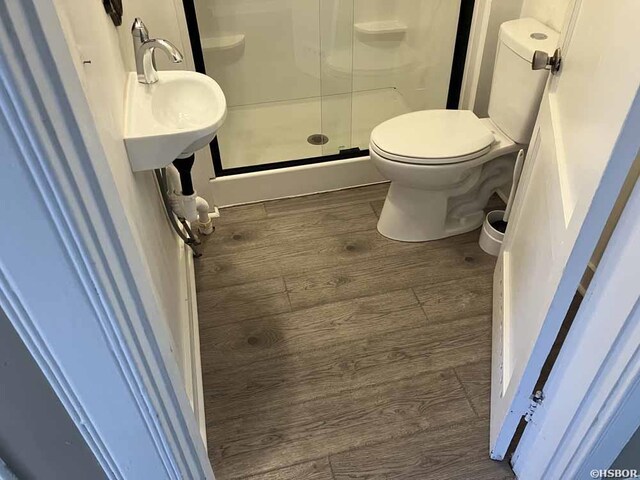 full bathroom featuring toilet, a shower stall, and wood finished floors