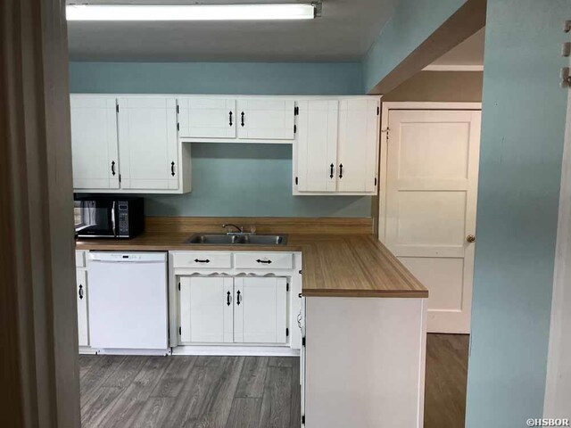 kitchen with black microwave, white dishwasher, a sink, and white cabinets