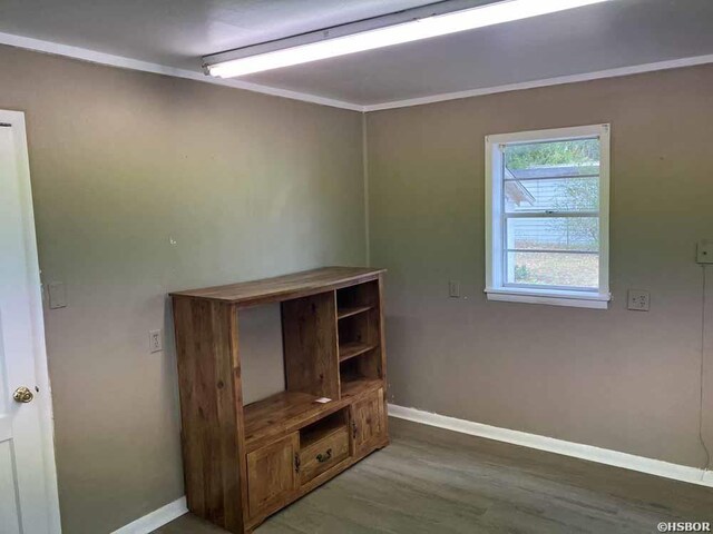 interior space featuring baseboards, wood finished floors, and ornamental molding