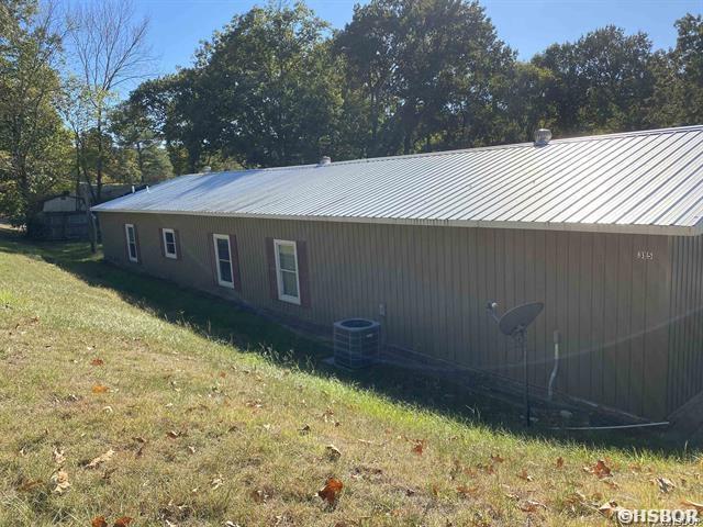 view of side of property with a lawn and central air condition unit