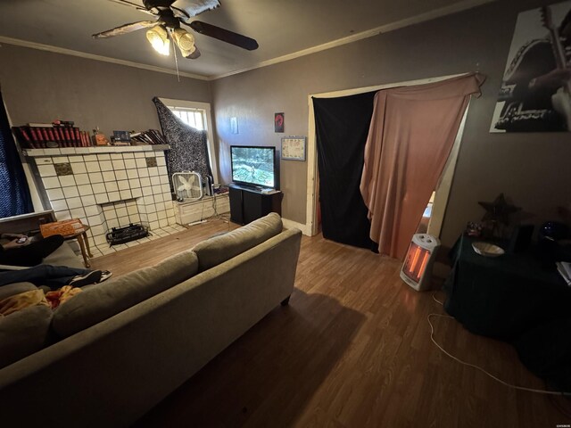 living area with baseboards, wood finished floors, a ceiling fan, and crown molding