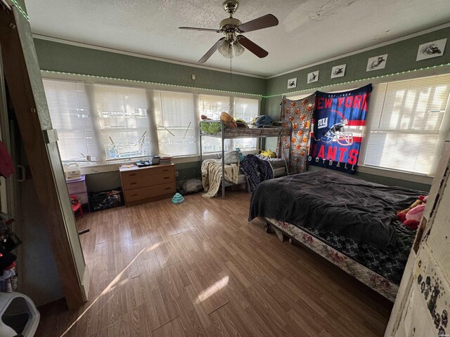 bedroom with ornamental molding, ceiling fan, a textured ceiling, and wood finished floors