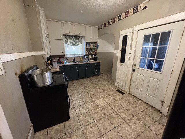 kitchen with visible vents, white cabinets, dark cabinets, a textured ceiling, and a sink