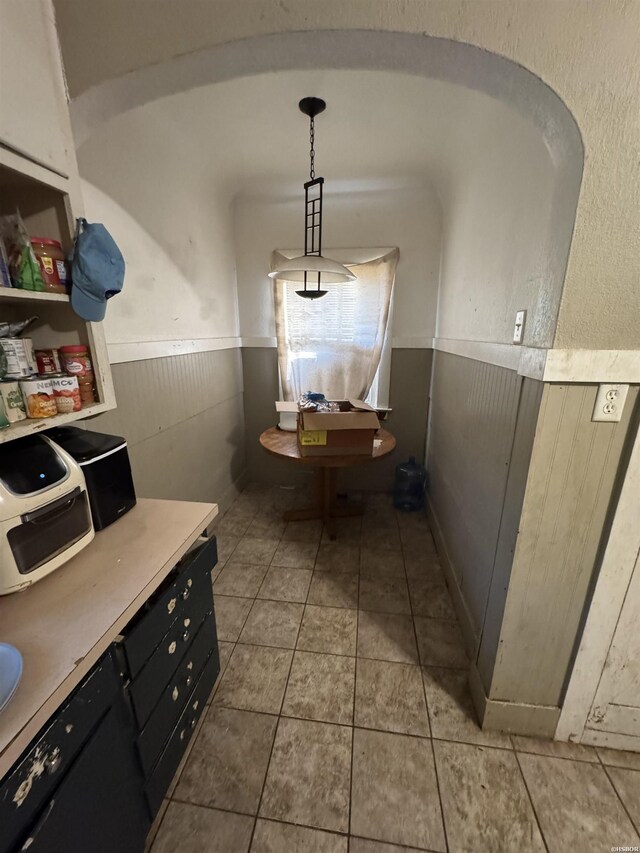 interior space with tile patterned floors, wood walls, and wainscoting