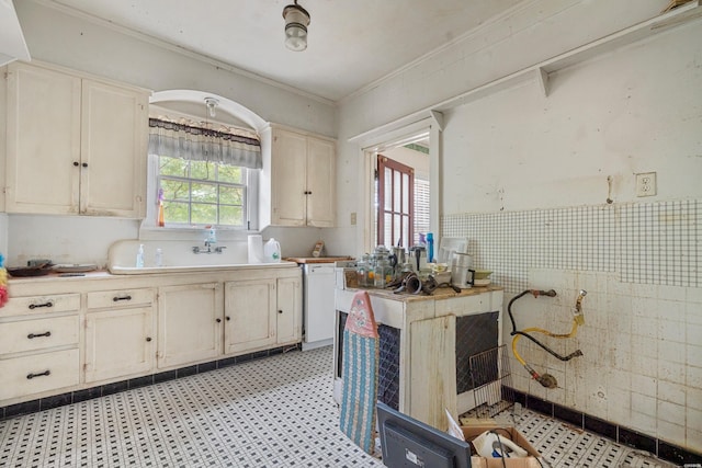 kitchen featuring white dishwasher, tile walls, light countertops, ornamental molding, and light floors