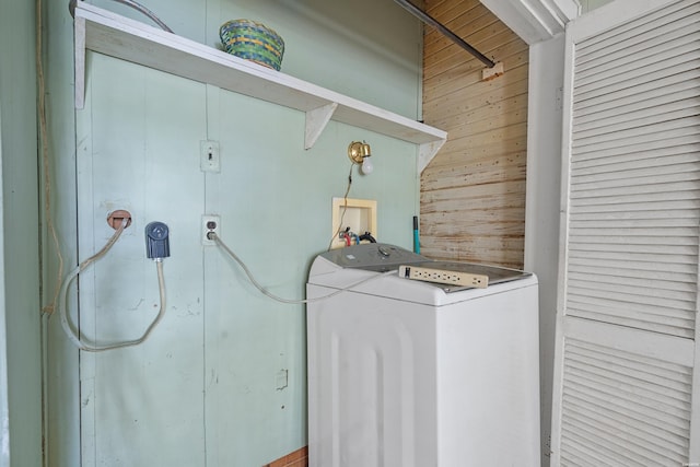 clothes washing area featuring washer / dryer, laundry area, and wood walls