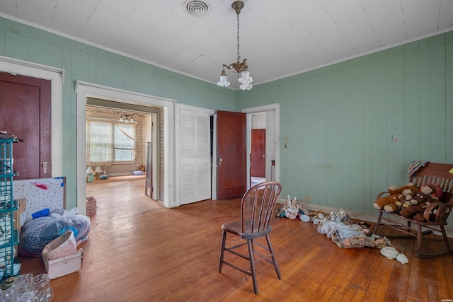 sitting room with visible vents, crown molding, an inviting chandelier, and wood finished floors