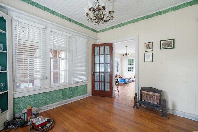 sitting room with ornamental molding, wood finished floors, and an inviting chandelier