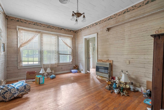 interior space with wood walls, wood finished floors, and heating unit