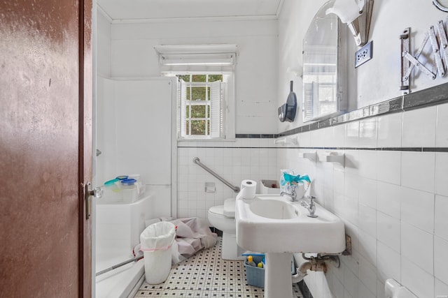 full bath with a wainscoted wall, crown molding, tile walls, toilet, and a shower stall