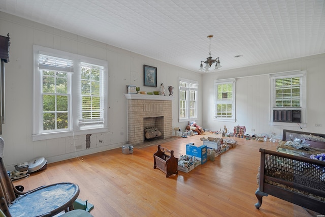 living room featuring a chandelier, a brick fireplace, and light wood finished floors