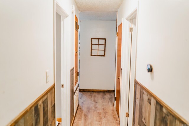 corridor featuring light wood finished floors and a textured ceiling