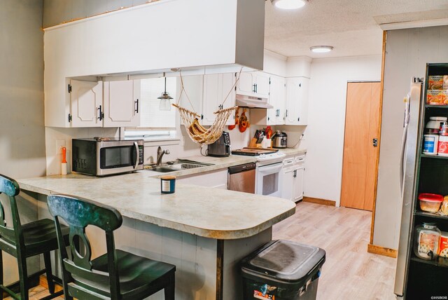 kitchen featuring under cabinet range hood, stainless steel appliances, a sink, white cabinets, and light countertops