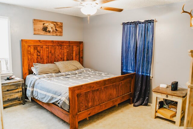 bedroom featuring light carpet, ceiling fan, and a textured ceiling