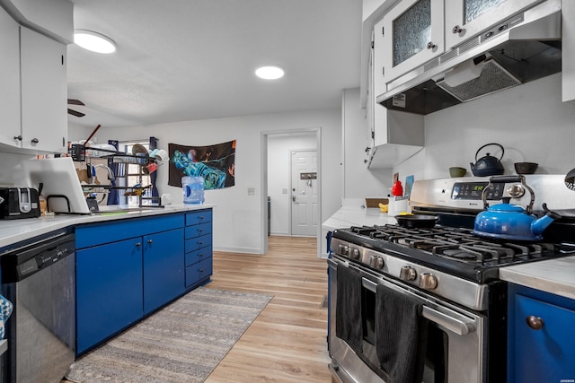 kitchen featuring light countertops, under cabinet range hood, light wood finished floors, stainless steel appliances, and blue cabinetry