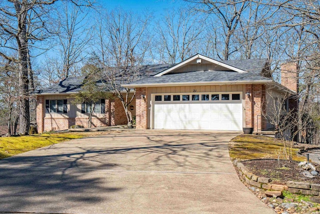 ranch-style home featuring an attached garage, brick siding, a shingled roof, driveway, and a chimney