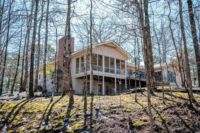 back of house with a sunroom and a chimney