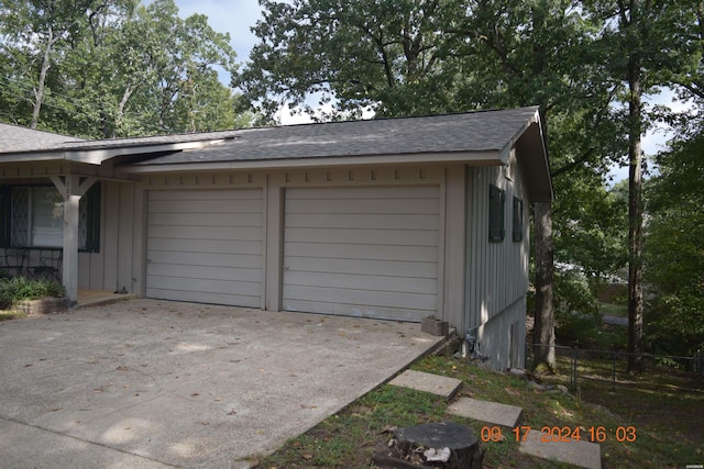 garage featuring driveway and fence