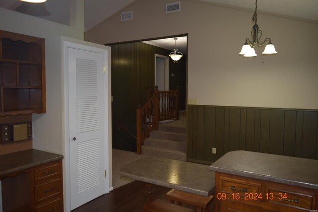 kitchen with a wainscoted wall, vaulted ceiling, visible vents, and decorative light fixtures