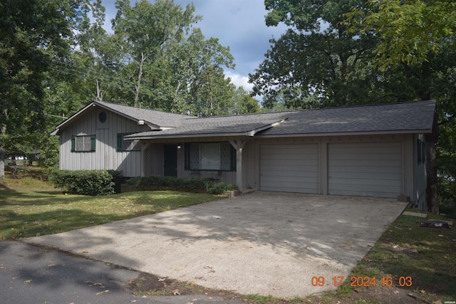 tri-level home featuring an attached garage, driveway, a front lawn, and roof with shingles