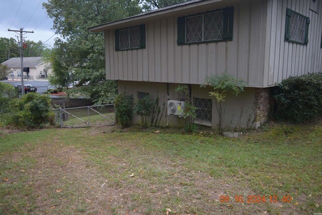 view of side of property with a yard, ac unit, and fence