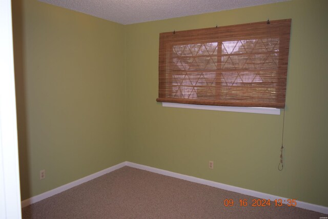 carpeted empty room with a textured ceiling and baseboards