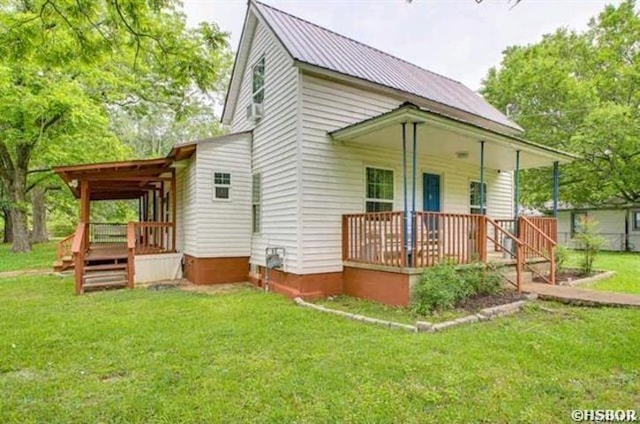 rear view of property featuring metal roof, a porch, and a lawn