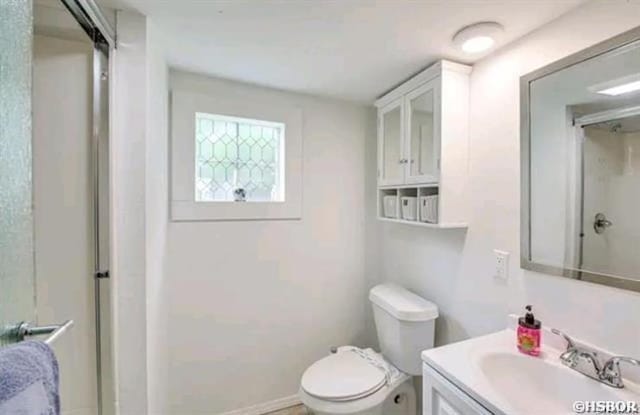 full bathroom featuring toilet, an enclosed shower, and vanity