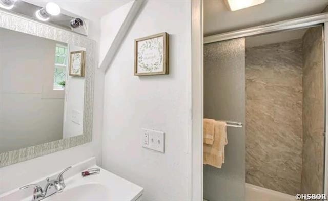 bathroom featuring a shower with door and vanity