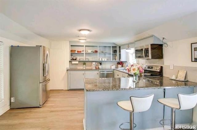 kitchen with a peninsula, appliances with stainless steel finishes, stone countertops, and white cabinets