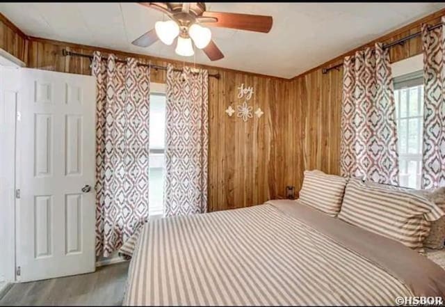 bedroom with wooden walls and a ceiling fan