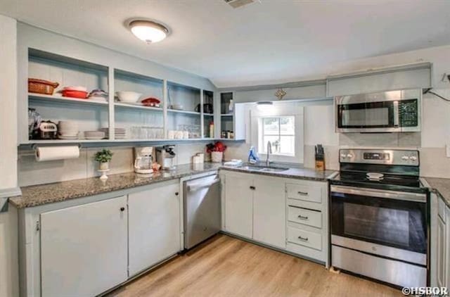 kitchen featuring white cabinets, appliances with stainless steel finishes, dark stone counters, open shelves, and light wood finished floors