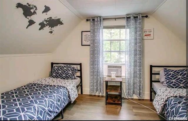 bedroom featuring vaulted ceiling, cooling unit, and wood finished floors