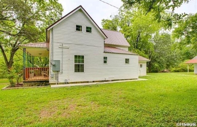 rear view of property featuring metal roof and a yard