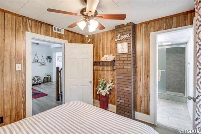 bedroom featuring a ceiling fan, visible vents, and wooden walls