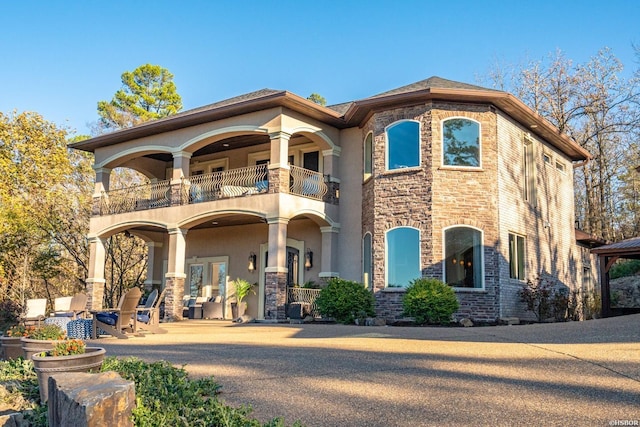 mediterranean / spanish-style house featuring french doors, a balcony, and stucco siding