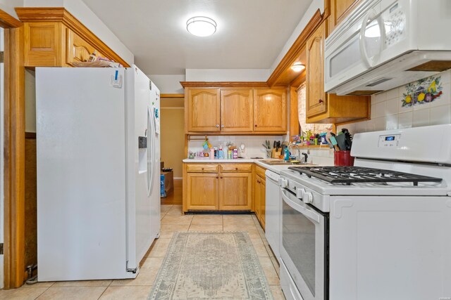 kitchen featuring light tile patterned floors, white appliances, a sink, light countertops, and backsplash