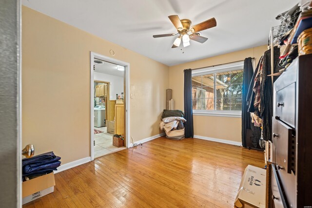 interior space with a ceiling fan, baseboards, wood finished floors, and washer / dryer