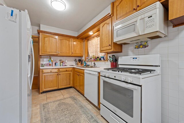 kitchen featuring light tile patterned flooring, white appliances, a sink, light countertops, and backsplash