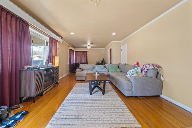 living room with crown molding, baseboards, and wood finished floors