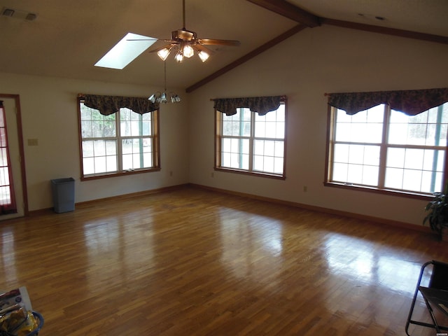 unfurnished living room featuring lofted ceiling with skylight, a healthy amount of sunlight, visible vents, and wood finished floors