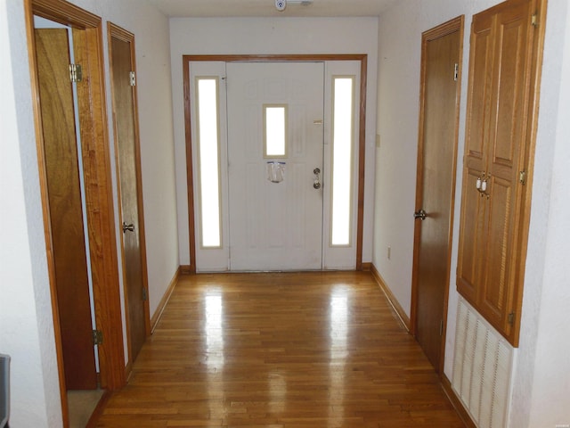 foyer featuring visible vents, baseboards, and wood finished floors