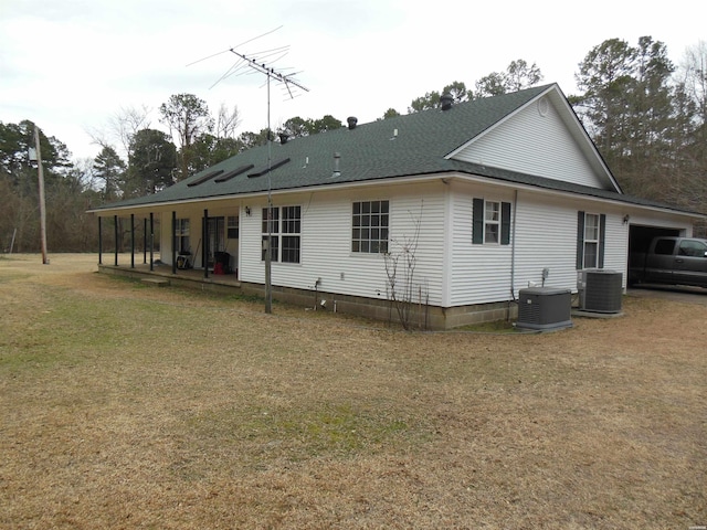 back of property with central AC, a shingled roof, and a lawn